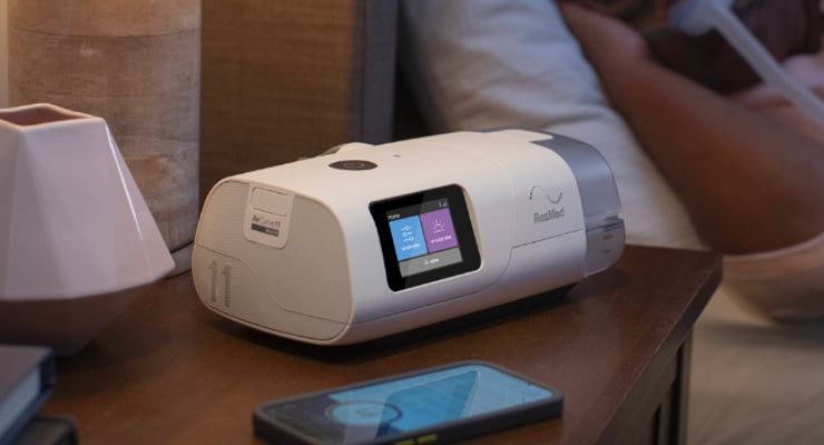 ResMed AirCurve 11 resting on a nightstand showing its slim and luxury appearance.