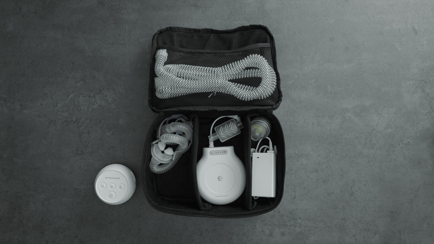 Transcend Micro travel bag opened with accessories neatly stored inside, including tubing, mask, battery, and charger, with the Transcend Micro machine placed outside of the case.