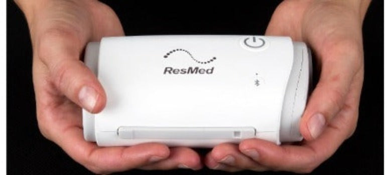 ResMed Airmini - Smallest Travel Machine showcasing its compactness while being held in a person's hands.