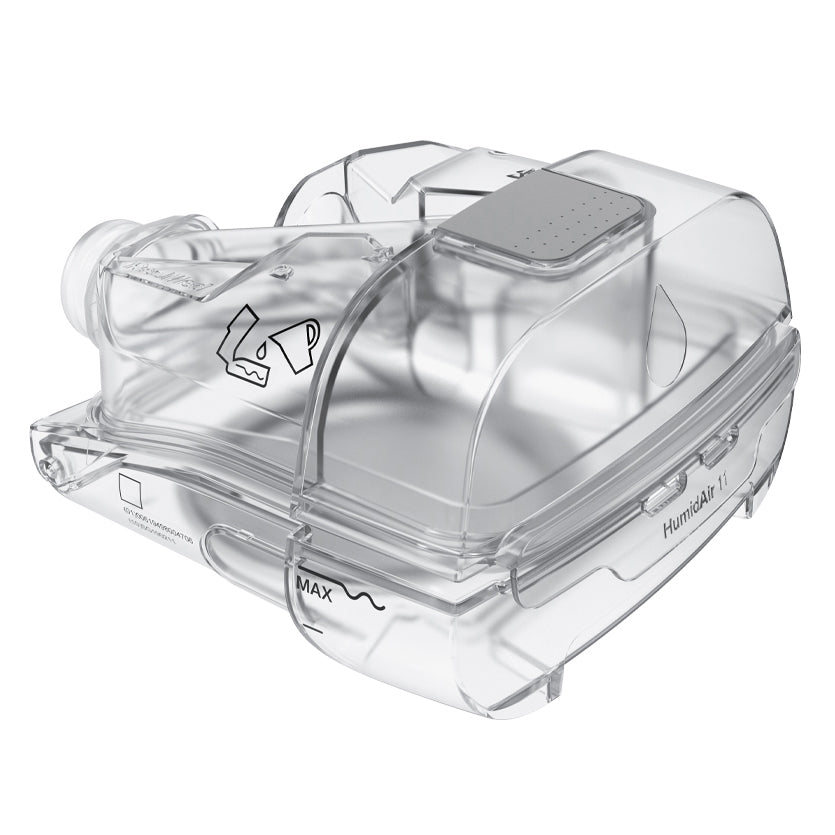 A close-up view of a transparent, cleanable water chamber used in the AirSense 11 AutoSet CPAP machines. The chamber is made from clear plastic and has a water level marker labeled "MAX." The chamber features a design for easy cleaning and maintenance.

